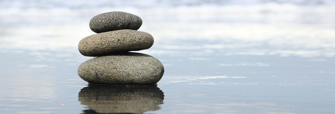 Stack of rocks resting on still water, serene scene.