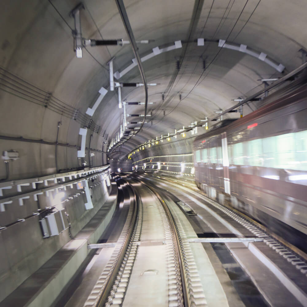 A train moving through a tunnel with a tunnel light illuminating the tracks.