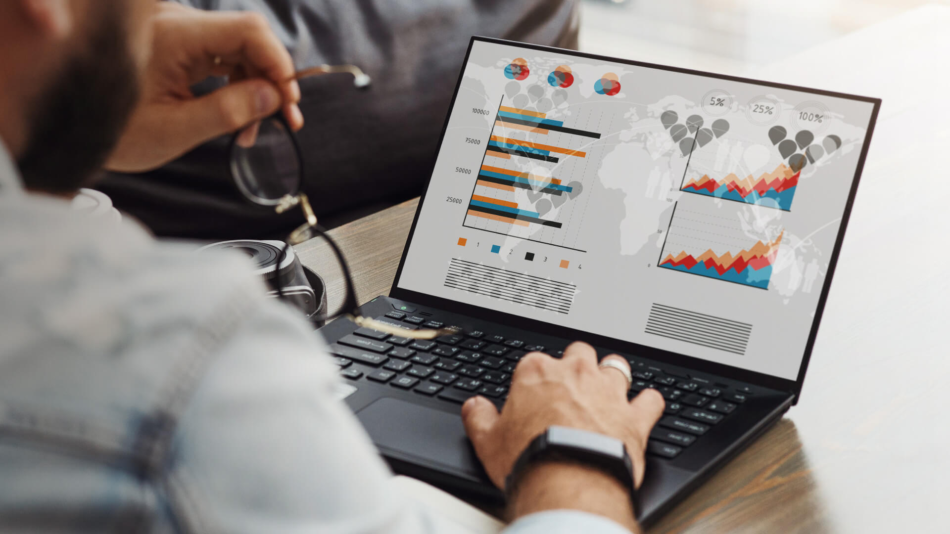 A man focused on a laptop displaying various graphs